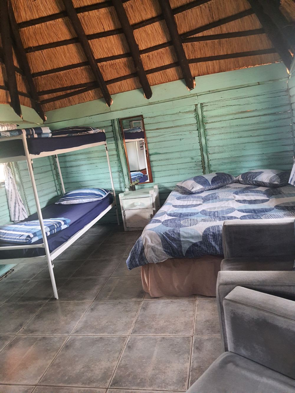 Inside a thatched chalet with double bed and bunk bed